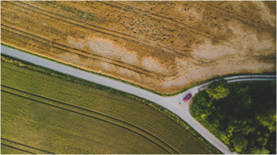 Aerial overhead view of a car driving through farmland